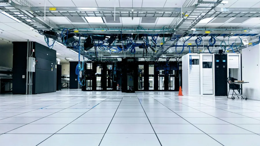 A working data center with server cabinets and overhead cabling, photographed by Taylor Vick.